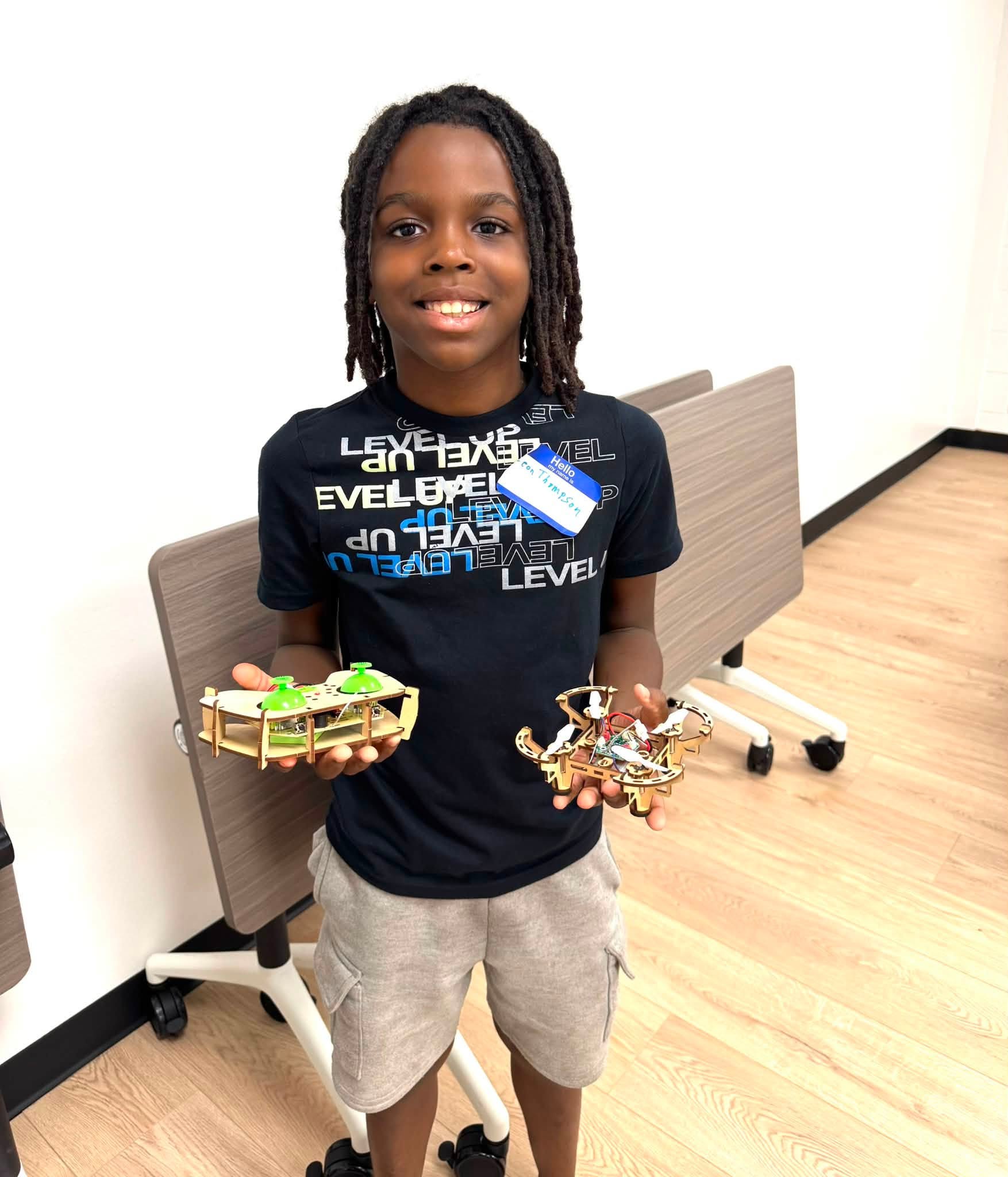 A boy holding a small drone and the remote control for it.